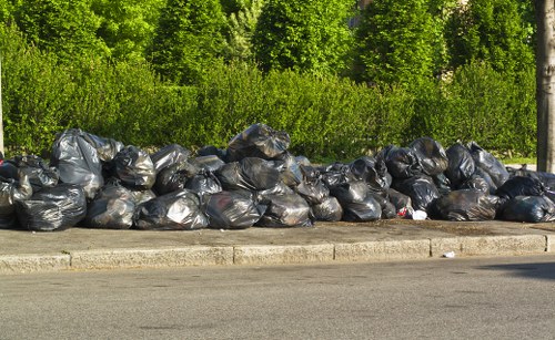 Worker wearing PPE inspecting waste containers at a commercial property